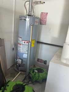 A water heater with holes cut in the wall above and below it on a Dunedin Leak Detection job.