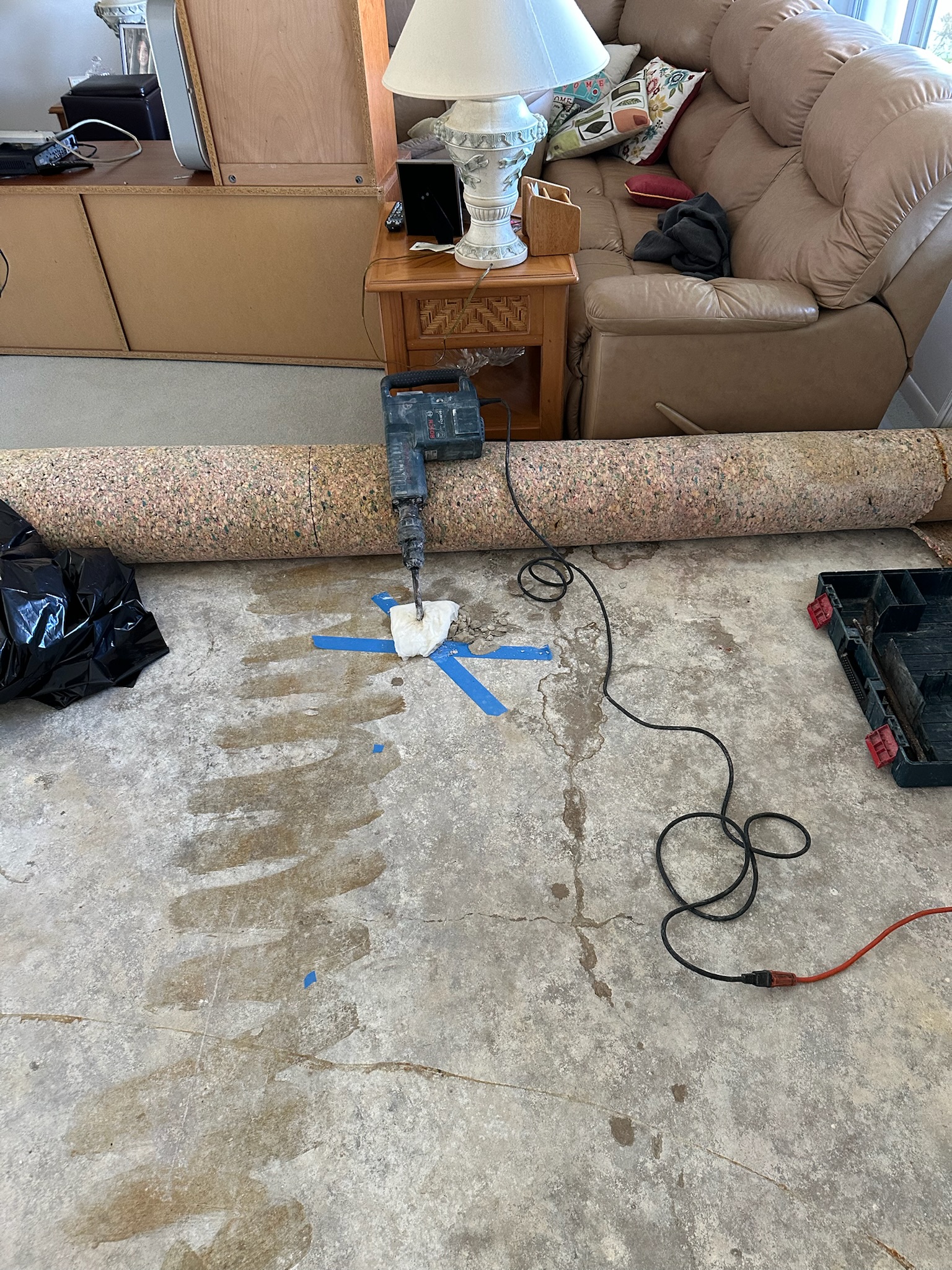 A blue X on a concrete floor under carpet marking the location of a slab leak in Seminole Florida.