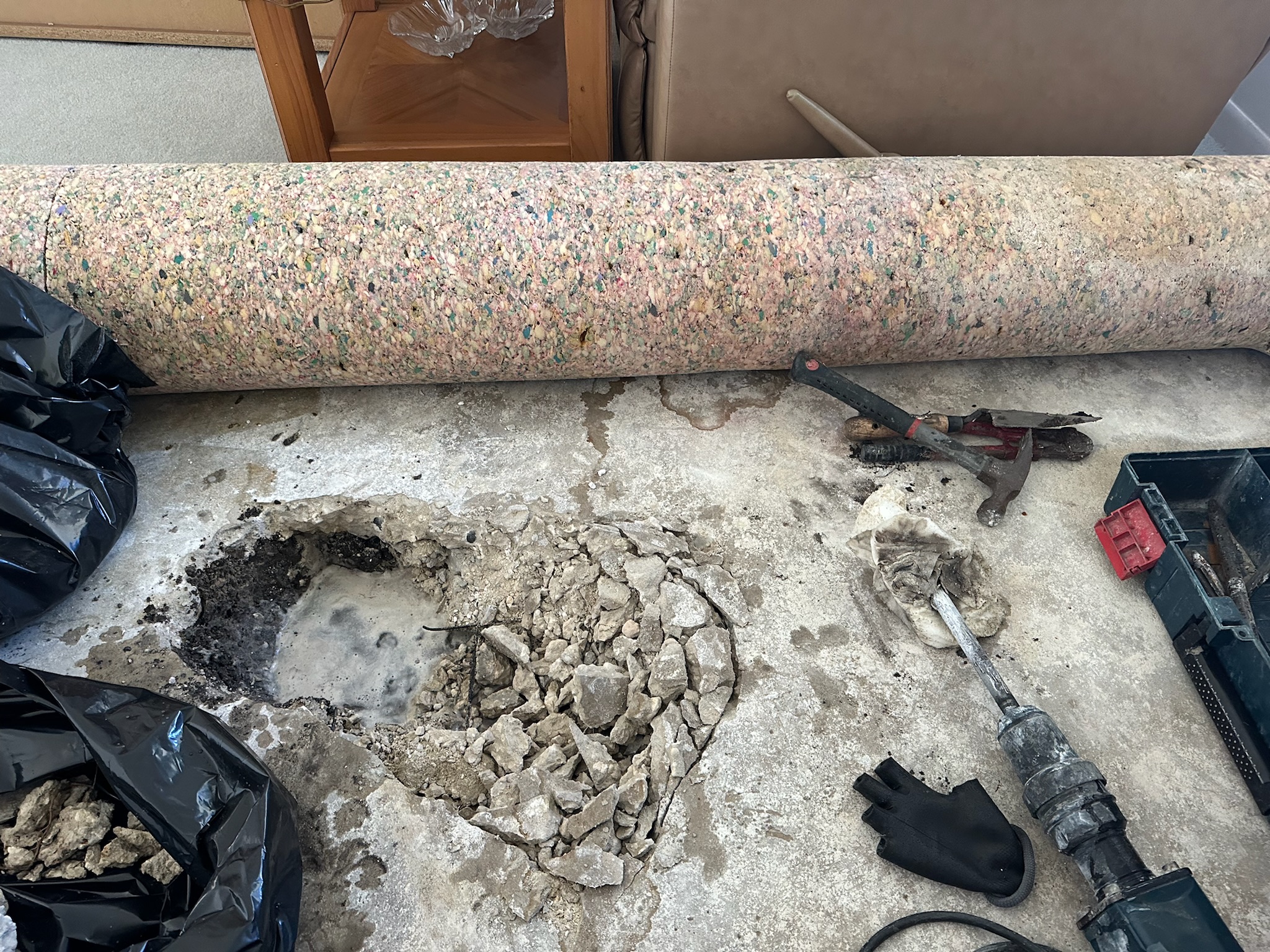 Carpet rolled back and concrete broken up in the process of exposing a slab leak in Seminole Florida.