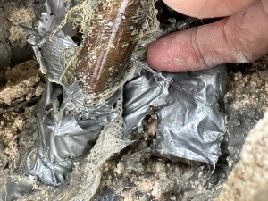 A Clearwater water leak in a block wall coming from a copper pipe with a finger in the image pointed at the leak.