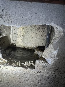 A hole in a concrete block wall filled with water with water dripping on a Pinellas Park leak detection job.