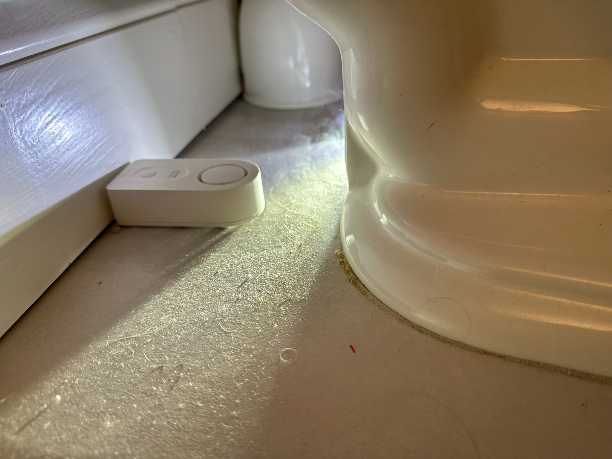 Smoke leaking from missing grout behind toilet during sewer odor test in Clearwater.