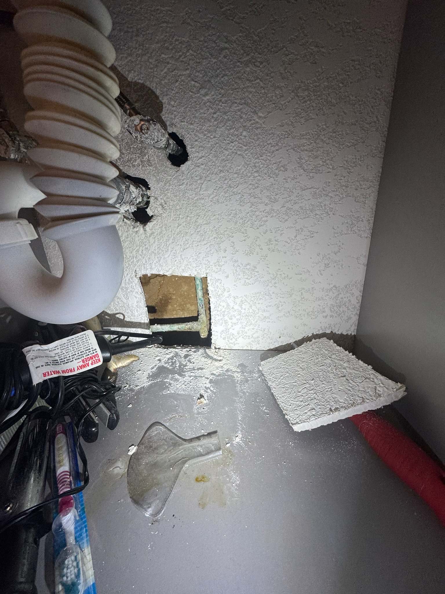 Close-up of small drywall access hole under vanity in Madeira Beach home leak detection