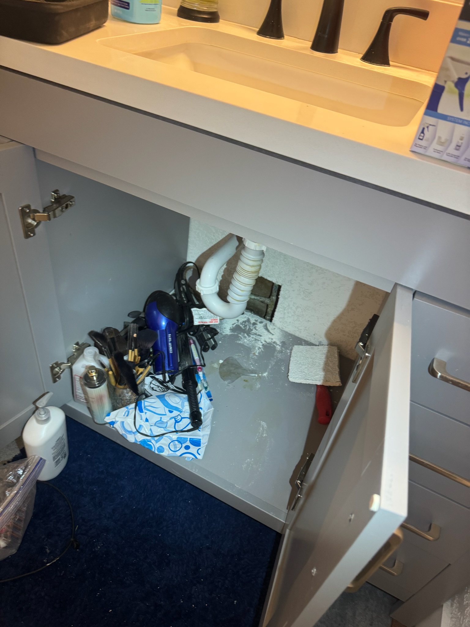 Neatly cut drywall access hole inside bathroom vanity cabinet in Madeira Beach home