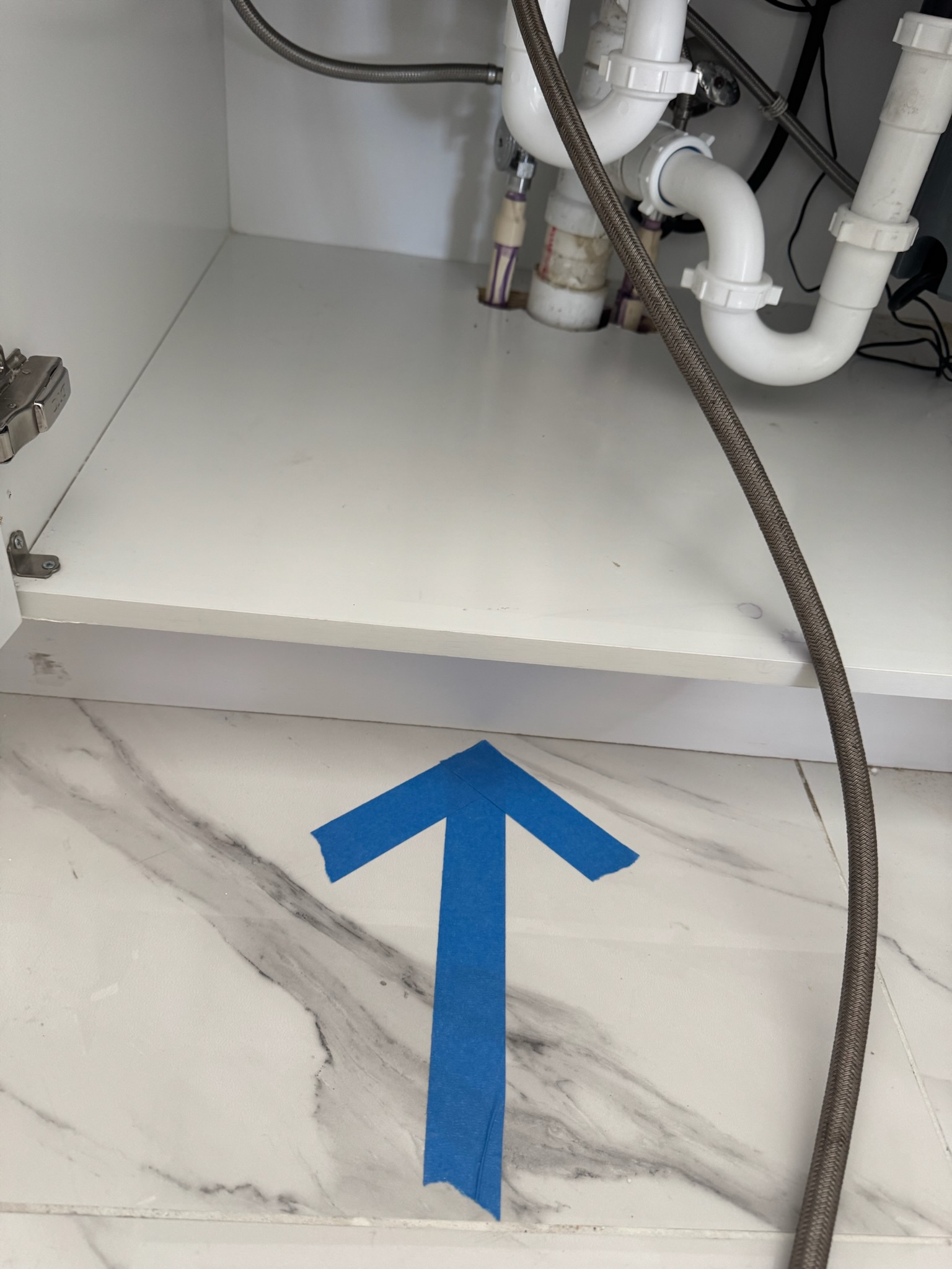 Blue arrow pointing under brand new kitchen cabinet in Oldsmar indicating slab leak location