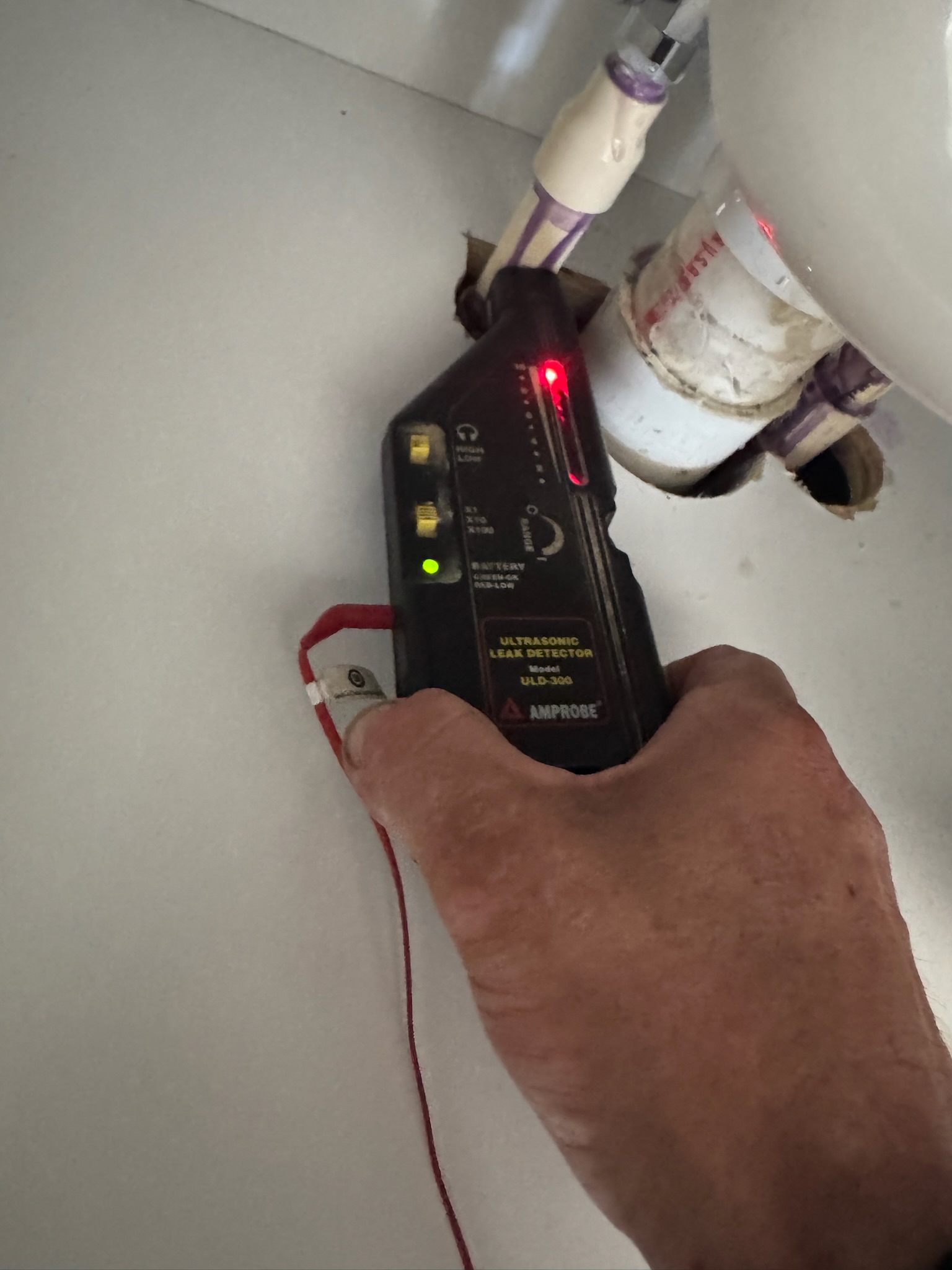 Ultrasonic leak detector pointing at CPVC pipe under brand new Oldsmar kitchen sink