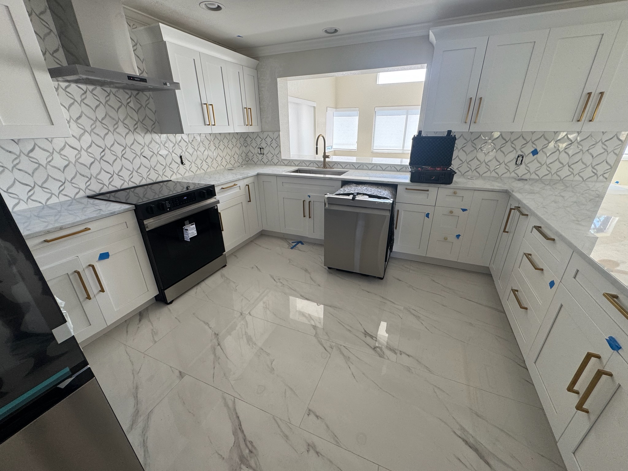 Wide view of newly remodeled Oldsmar kitchen with unused appliances and brand new flooring