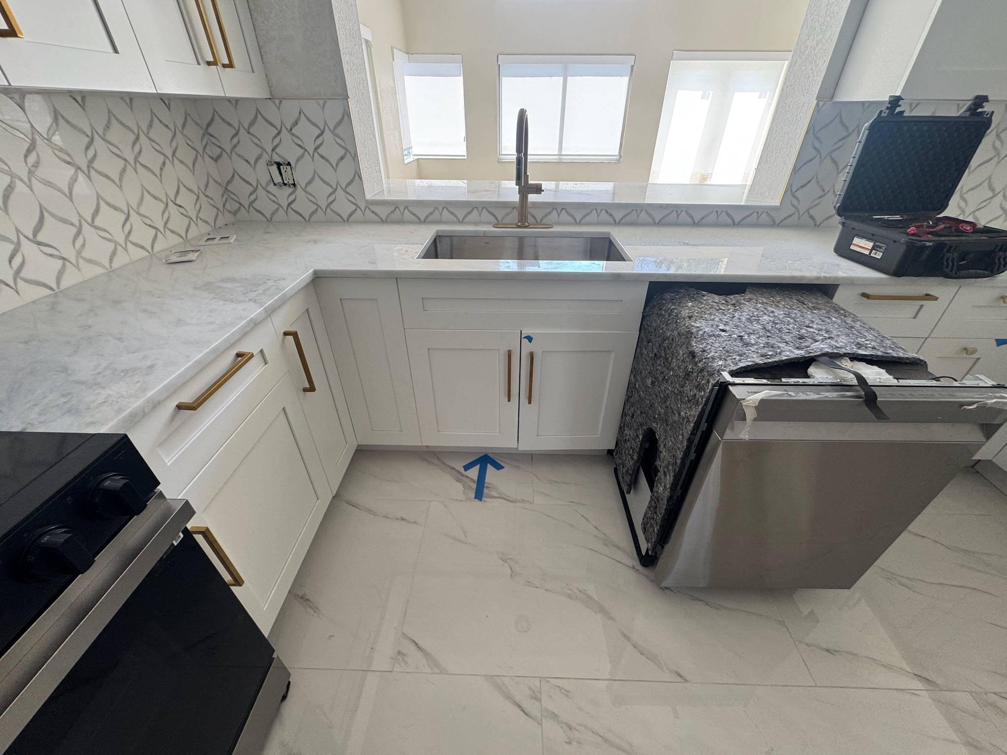 Brand new Oldsmar kitchen with dishwasher pulled out and leak detection equipment on counter