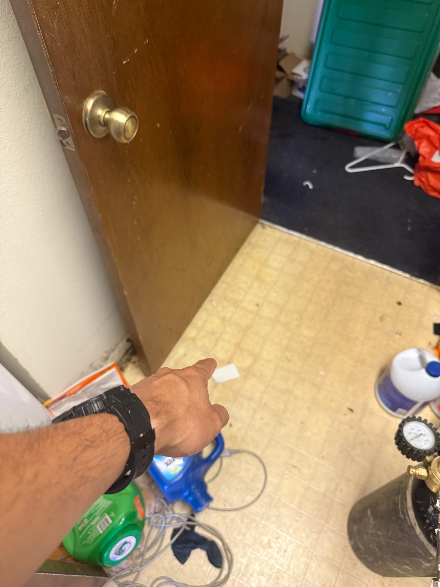Leak detection technician pointing to suspected slab leak location in cluttered hoarder house