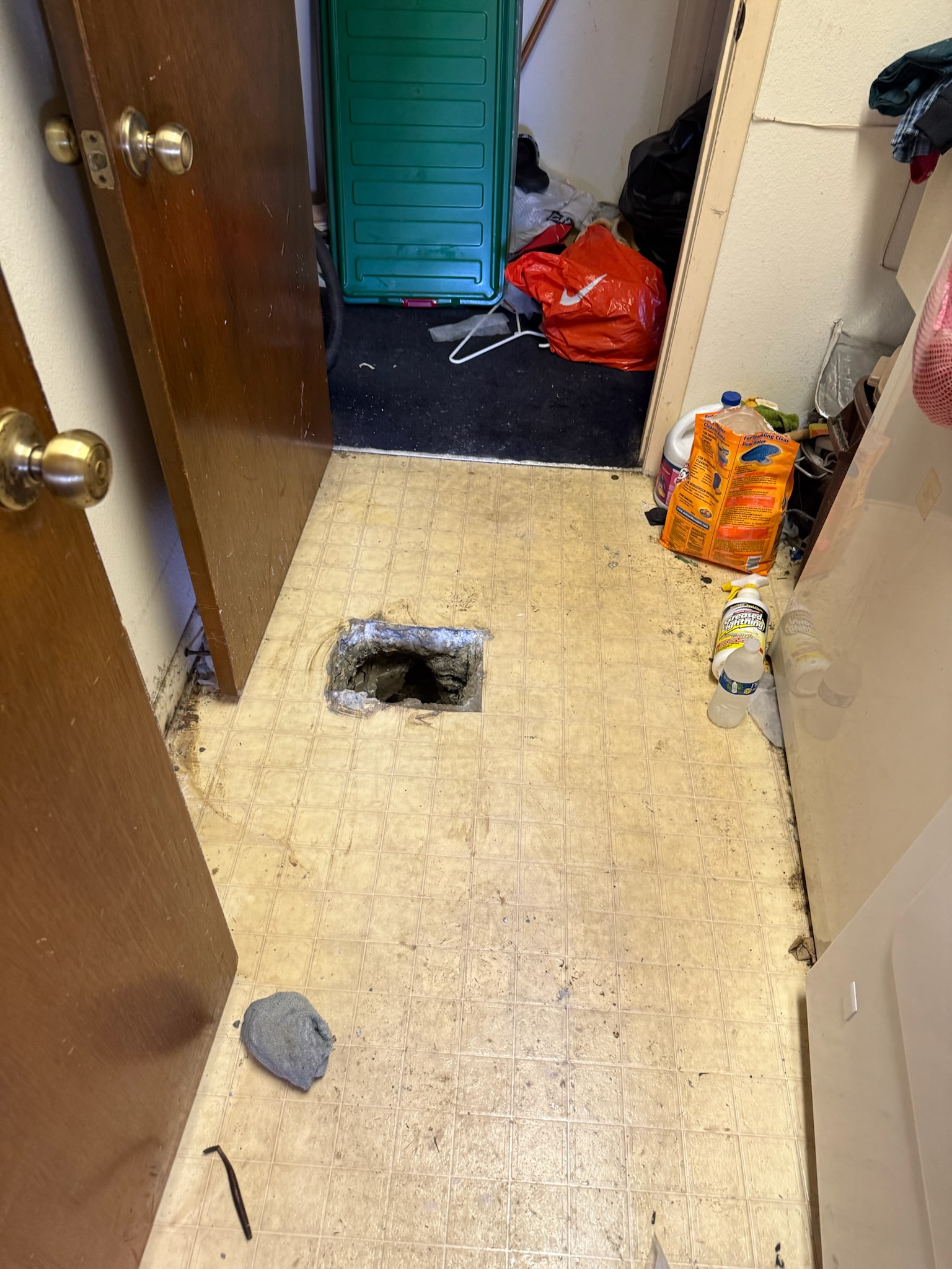 Small square hole cut in linoleum floor exposing exact location of slab leak