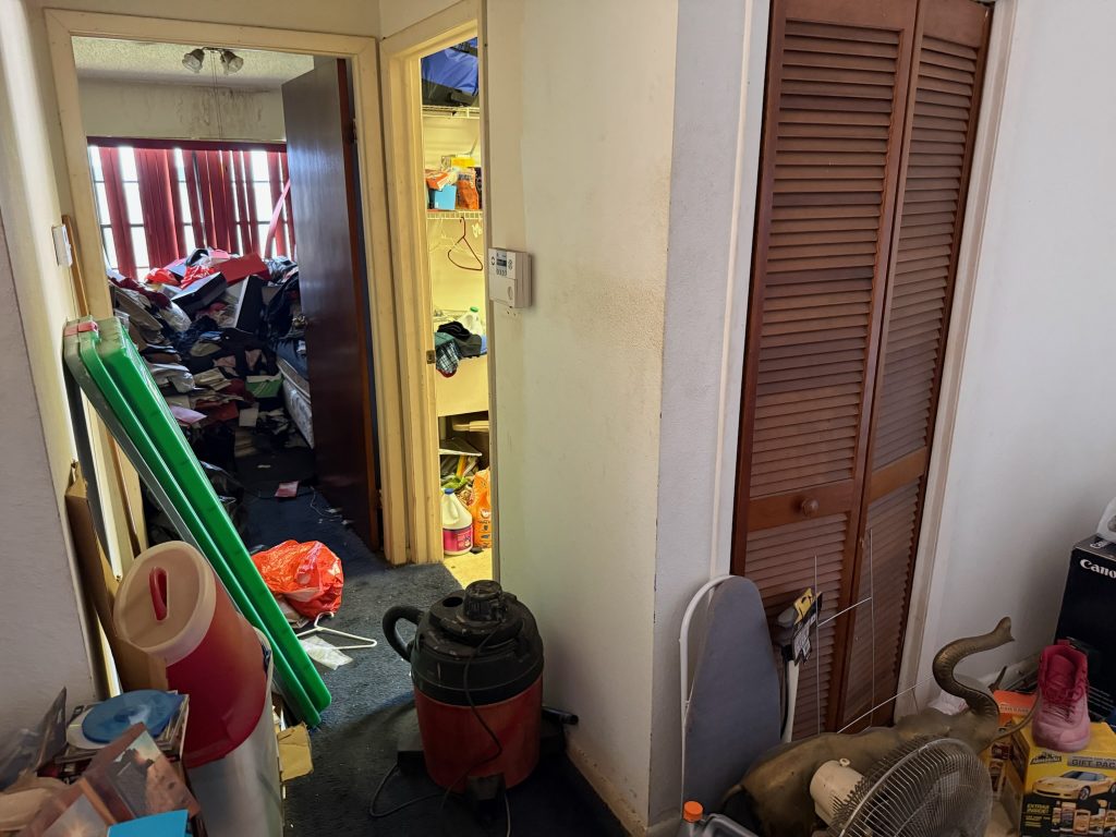 Cluttered interior of a hoarder house with household items stacked nearly six feet high