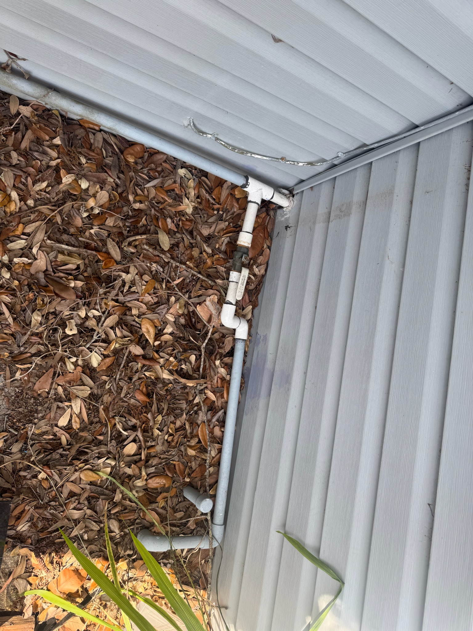 Gray-painted PVC pipe with brass ball valve leading into the ground