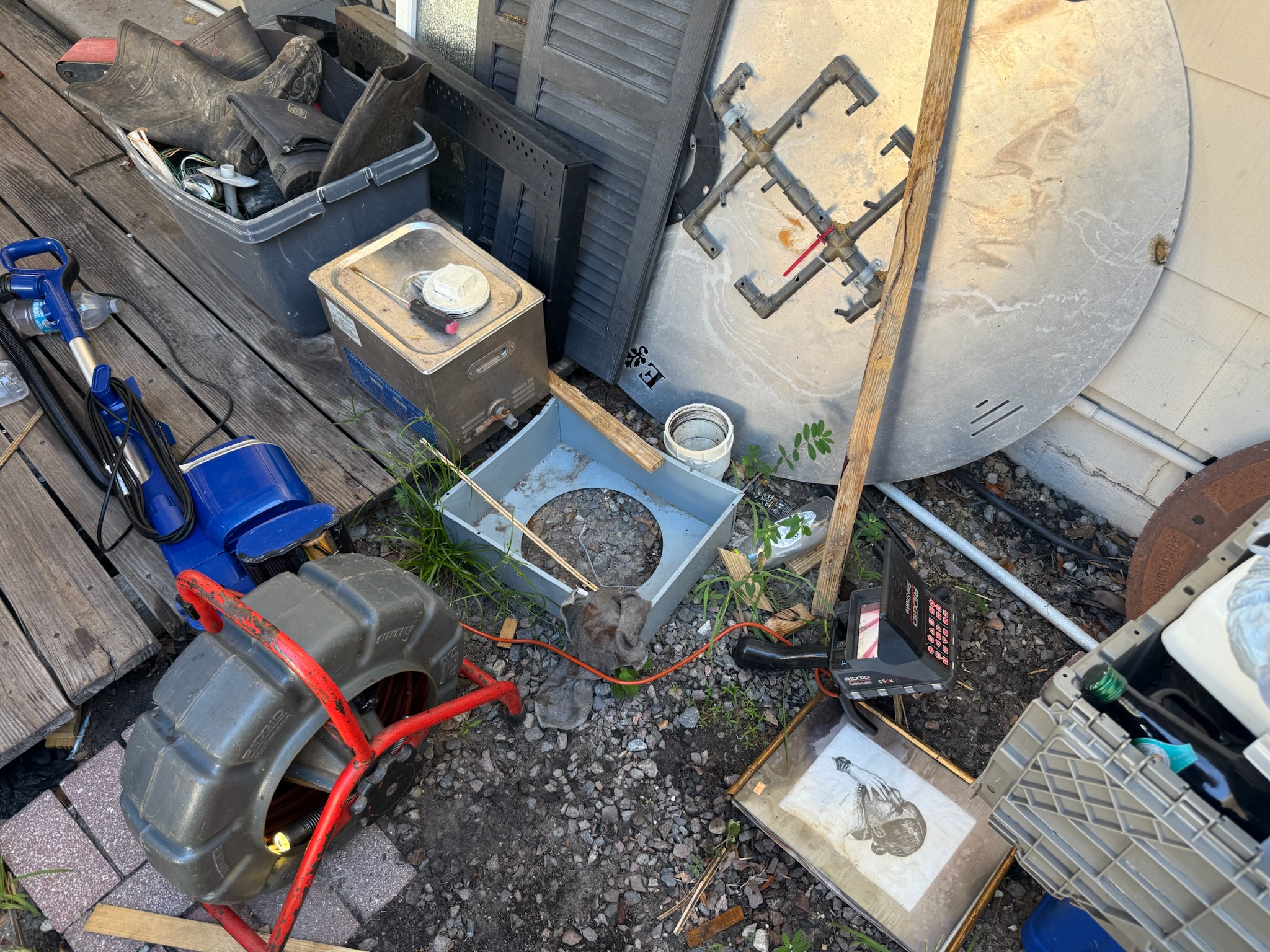 Rigid sewer camera reel on the ground beside Clearwater home before rooftop sewer inspection