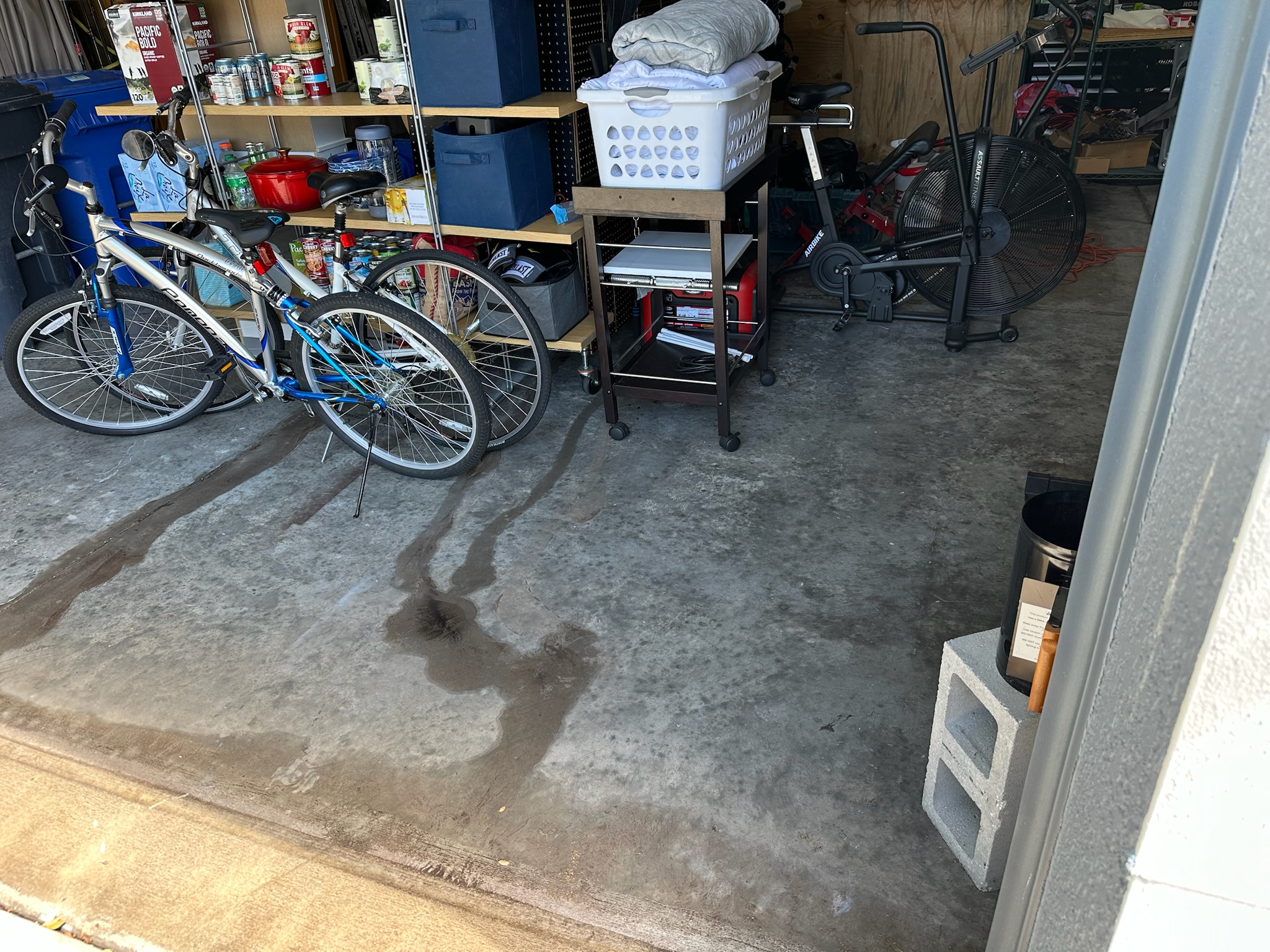 Water leaking through garage cracks beneath shelving and bicycles at Tampa home