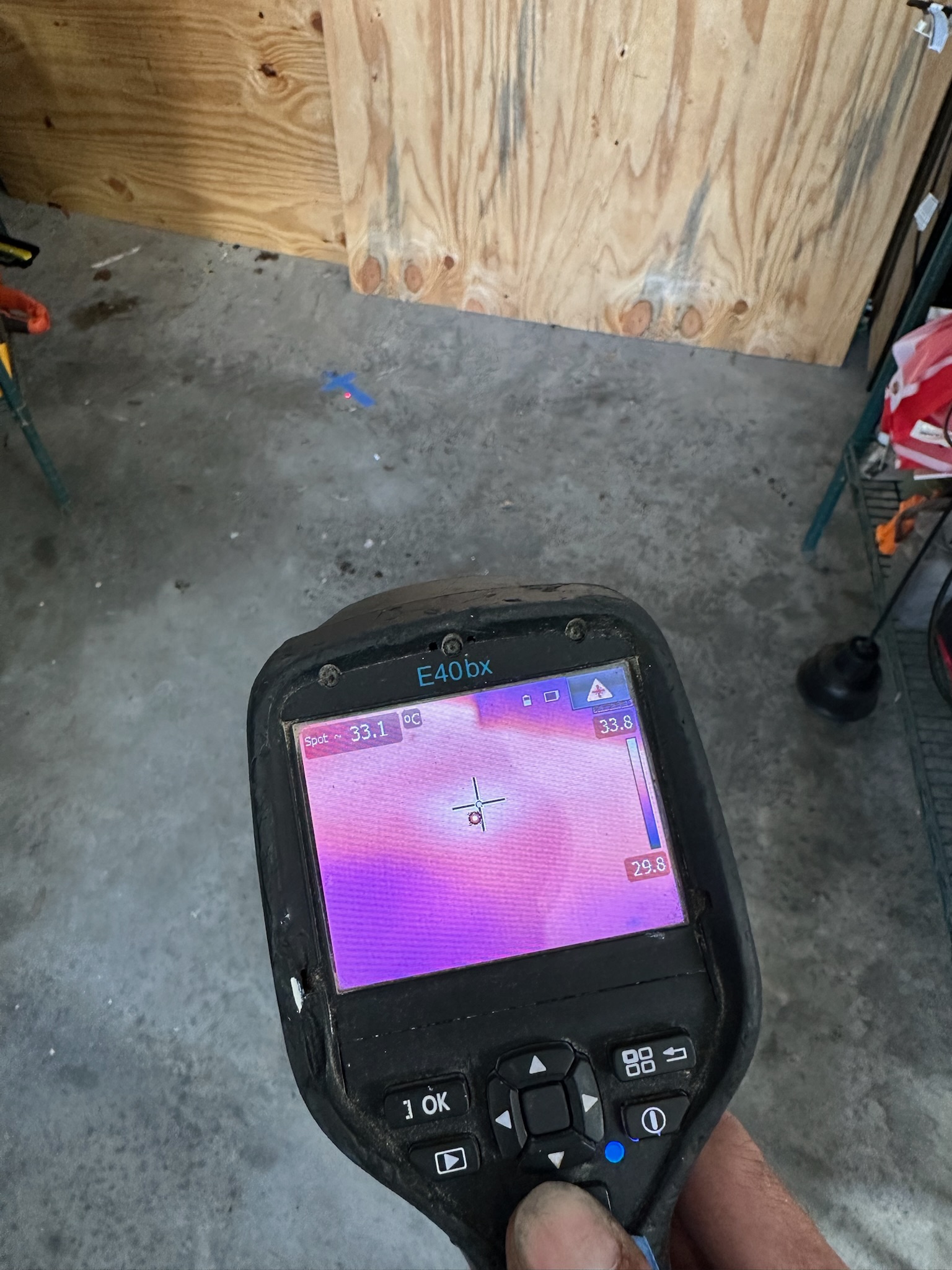 Leak detection technician using infrared camera on dry garage floor in Tampa