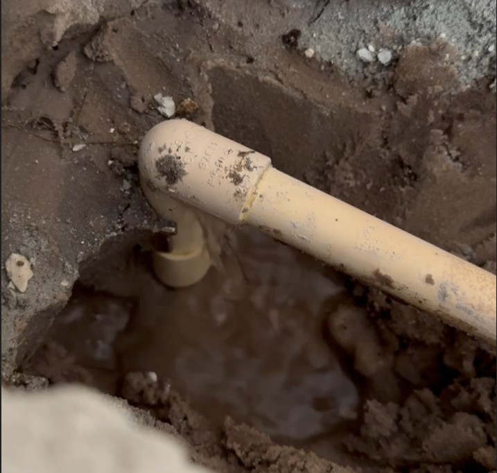 Water spraying from leaking 90-degree CPVC pipe fitting under Tampa home