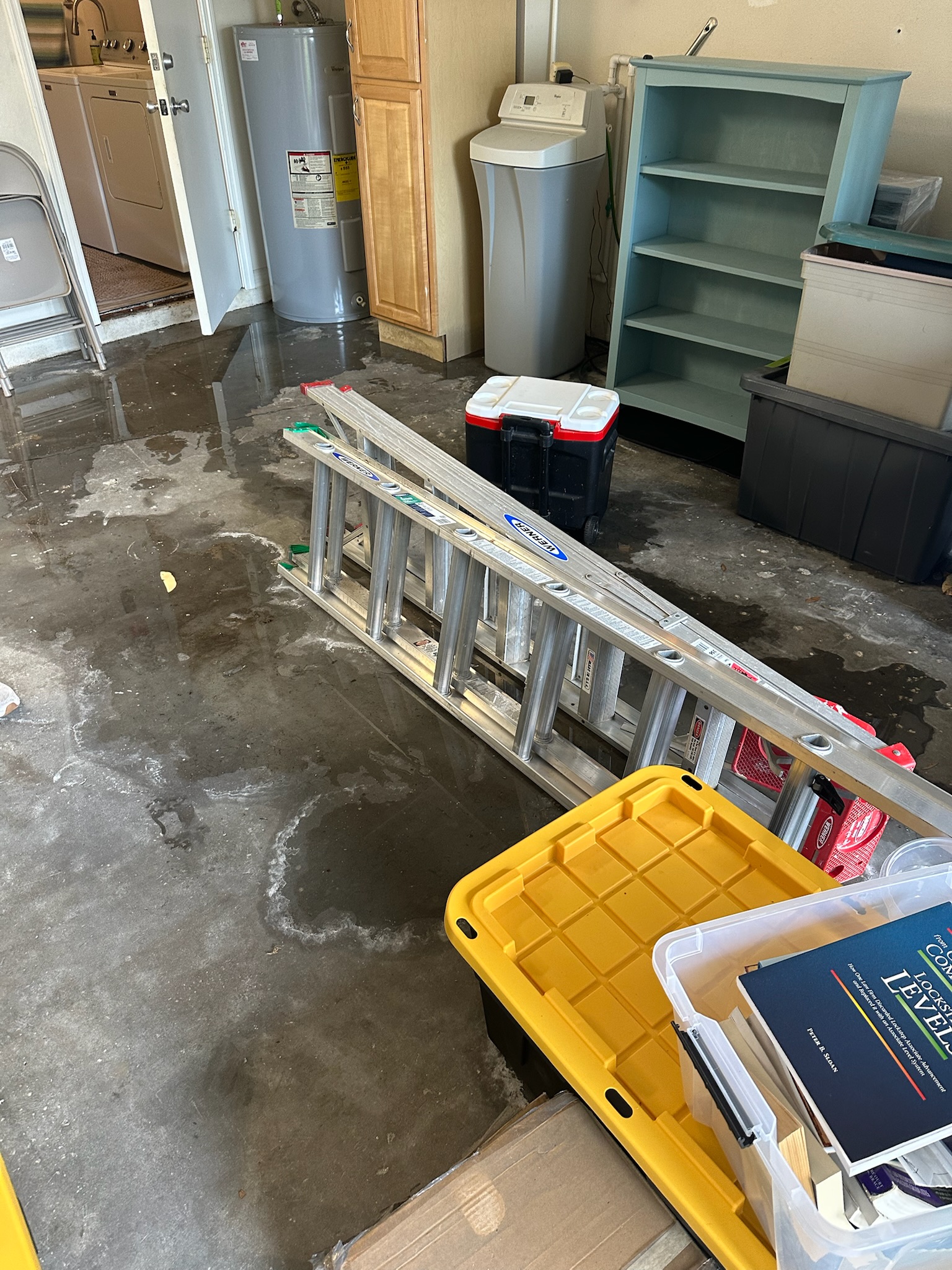 Water puddle forming in a Westchase garage, possibly from a hidden leak near the water heater.