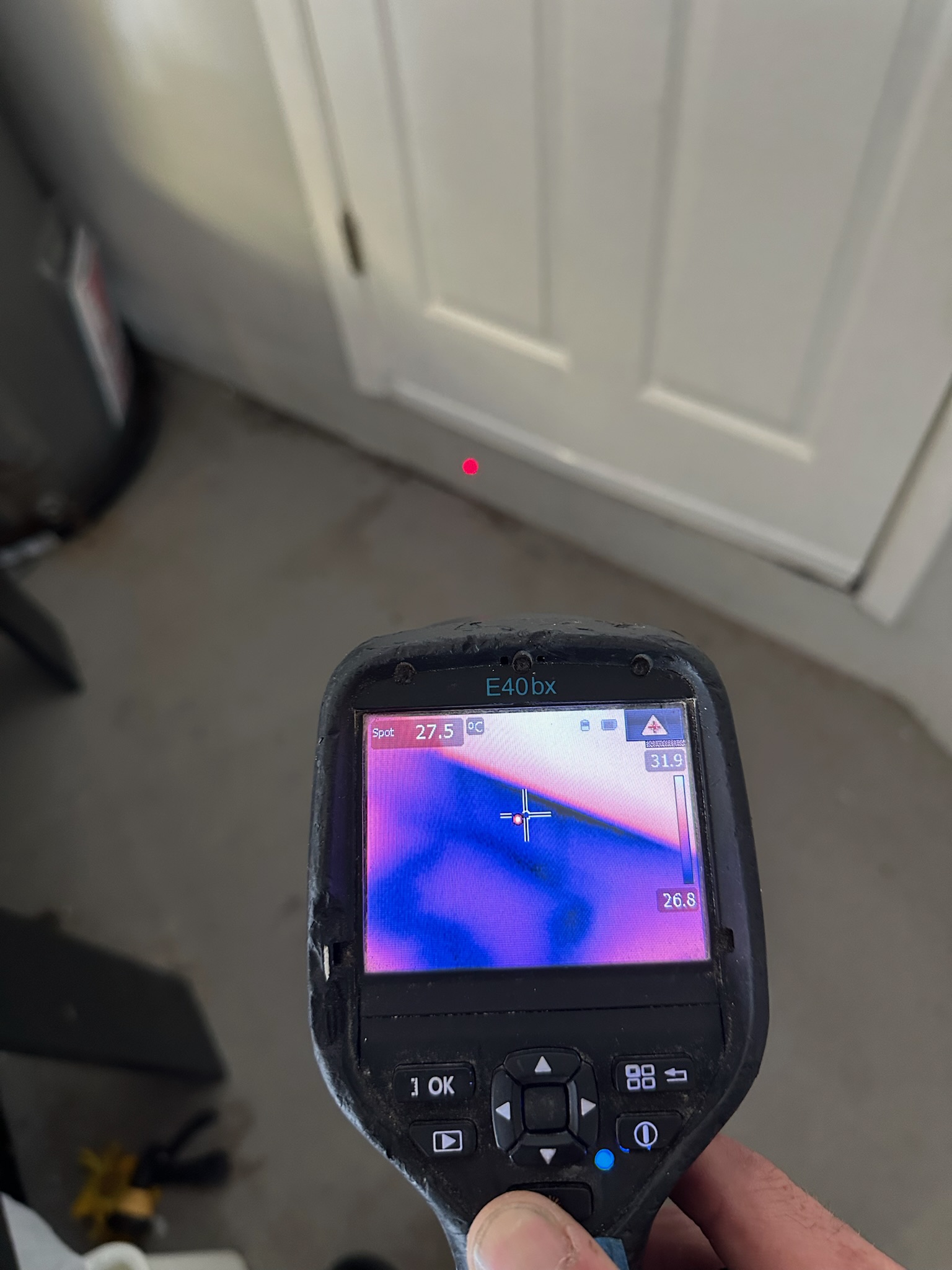 Tyler uses an infrared camera to check for moisture at the base of a garage doorway, where water was appearing unexpectedly.