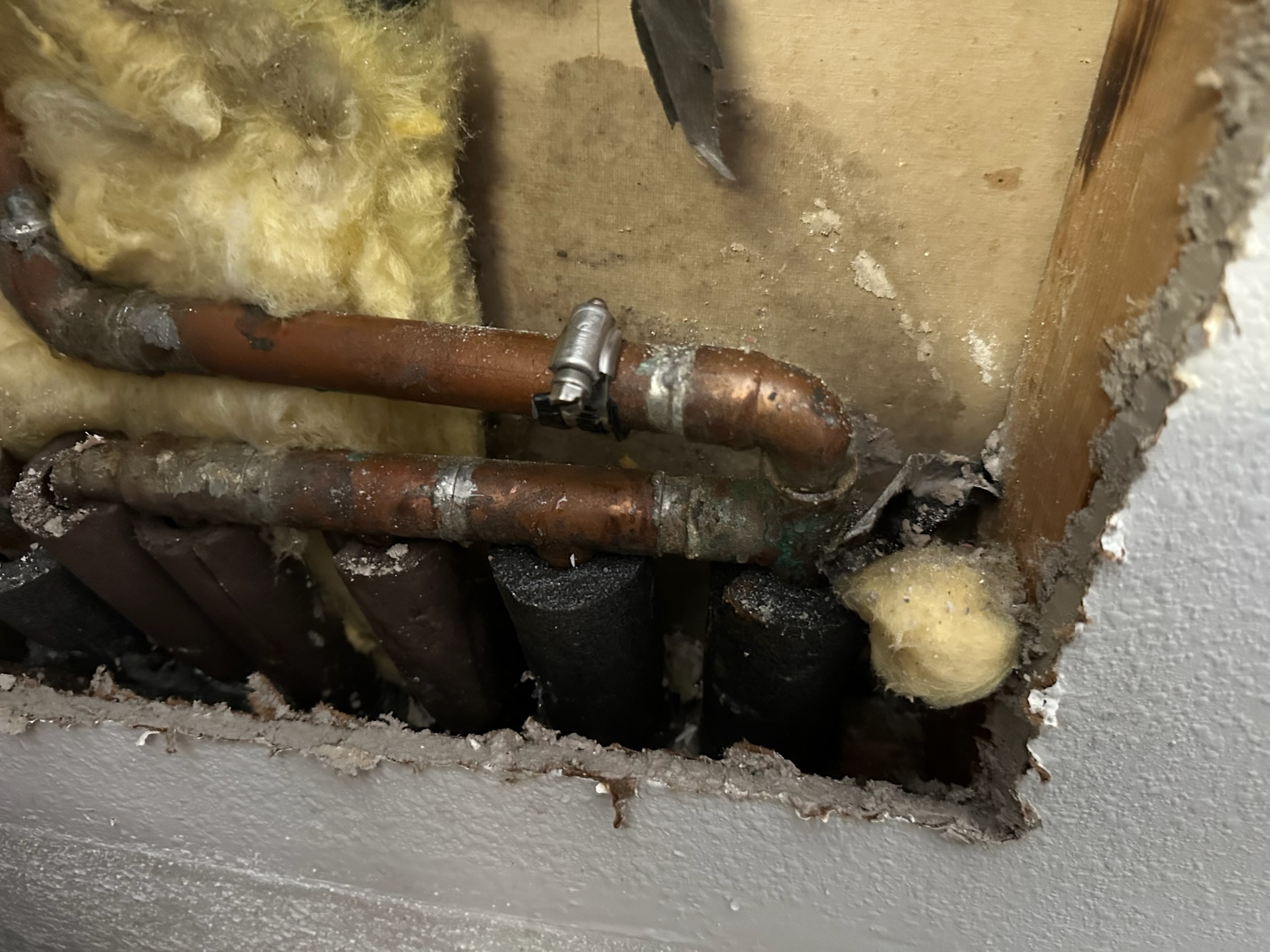 Tyler installs a temporary rubber patch and clamp on a copper pipe to stop the leak until a plumber can make permanent repairs.