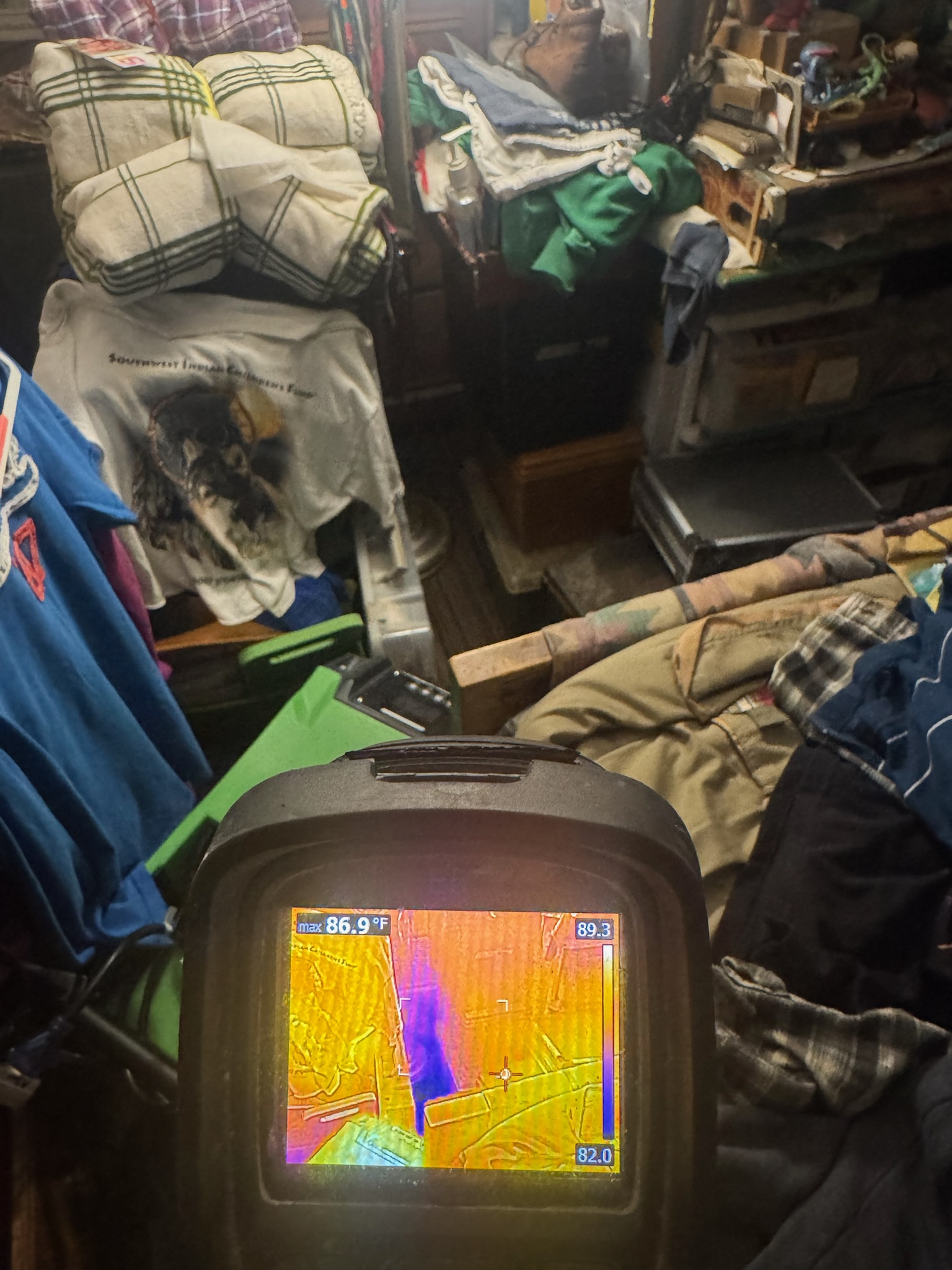 I Find Leaks technician using infrared camera to detect moisture in cluttered Clearwater home