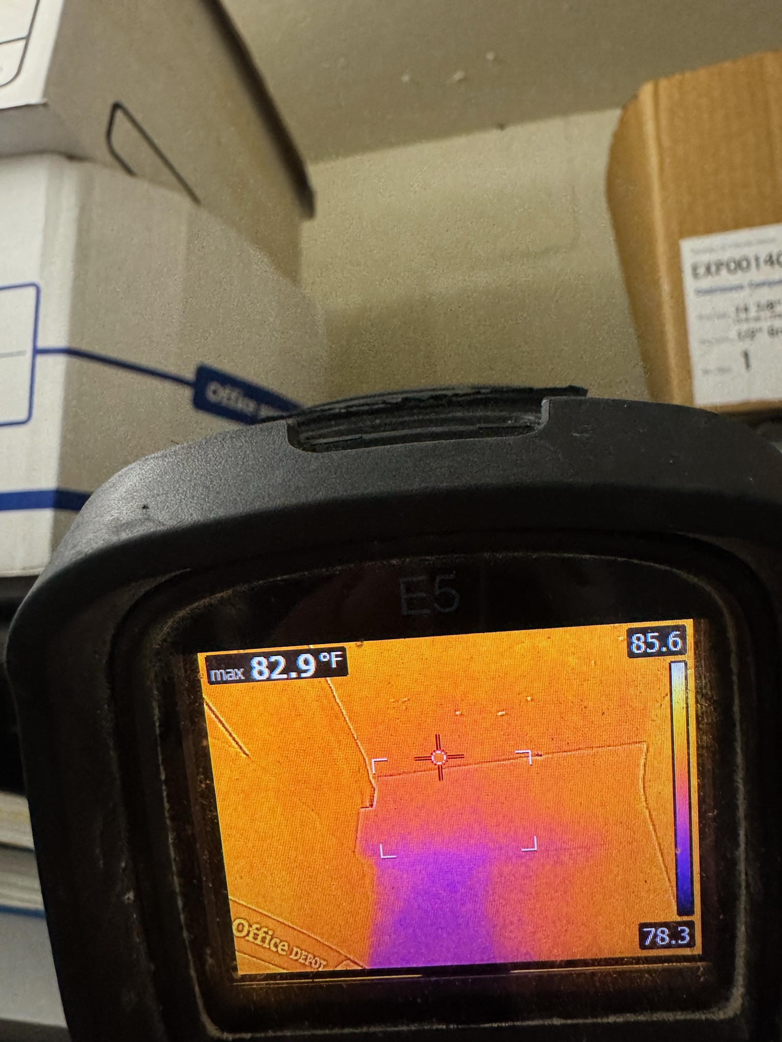 Jeremy scanning a wall for moisture using a FLIR infrared camera in a Clearwater Beach condo room with storage boxes