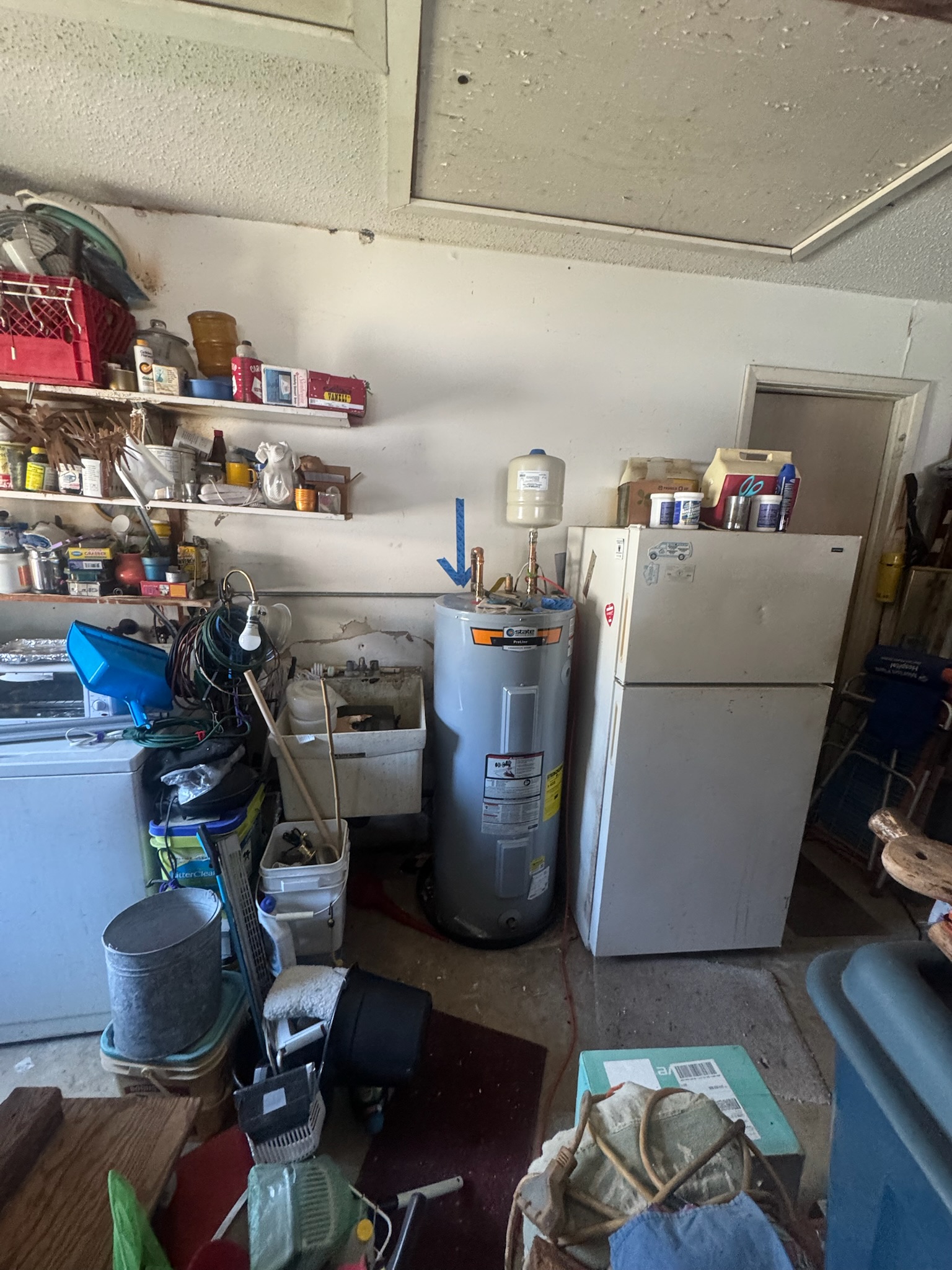 Blue tape marks leak location on garage wall behind water heater in Clearwater home