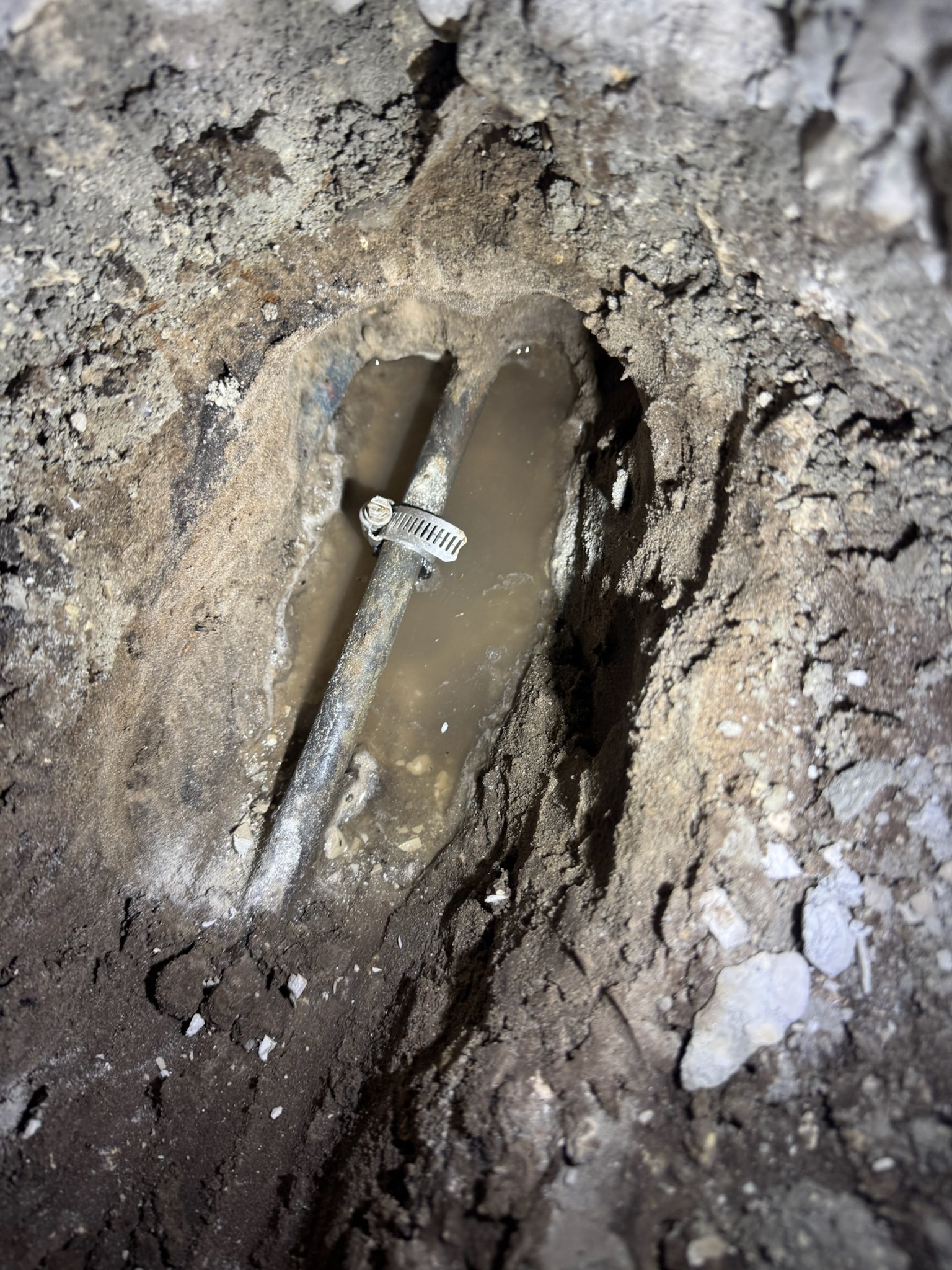 Copper pipe slab leak exposed under wall in Clearwater with temporary patch installed