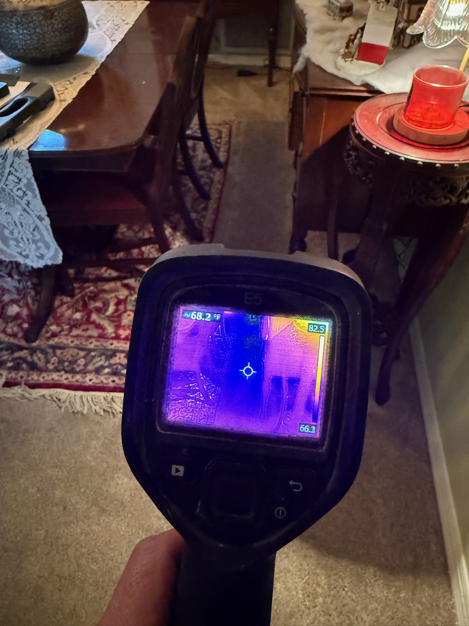 Infrared leak detection specialist scanning carpet for hidden moisture using a thermal imaging camera