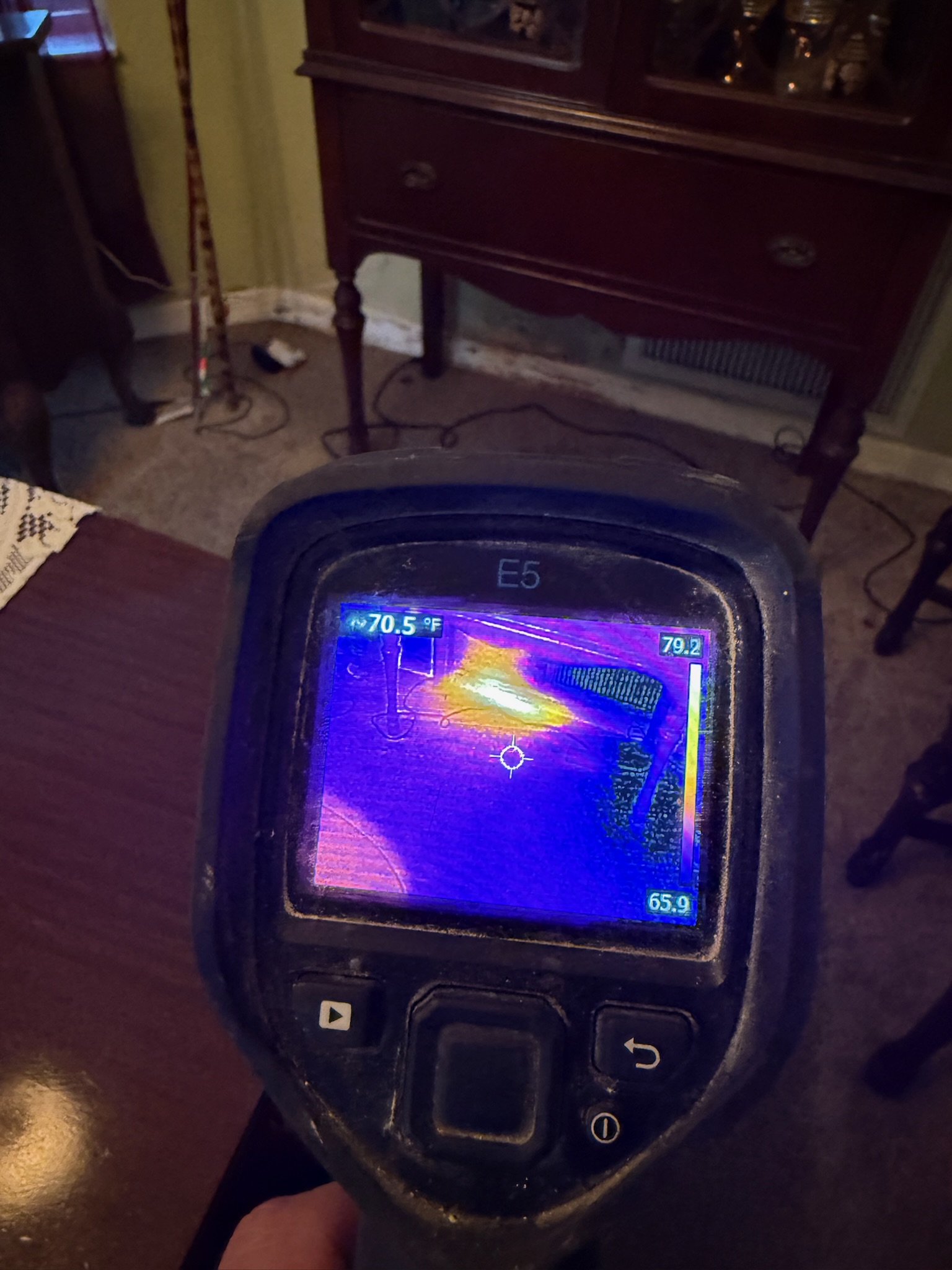 Non-invasive leak detection showing moisture under carpet near a wall beneath a curio cabinet