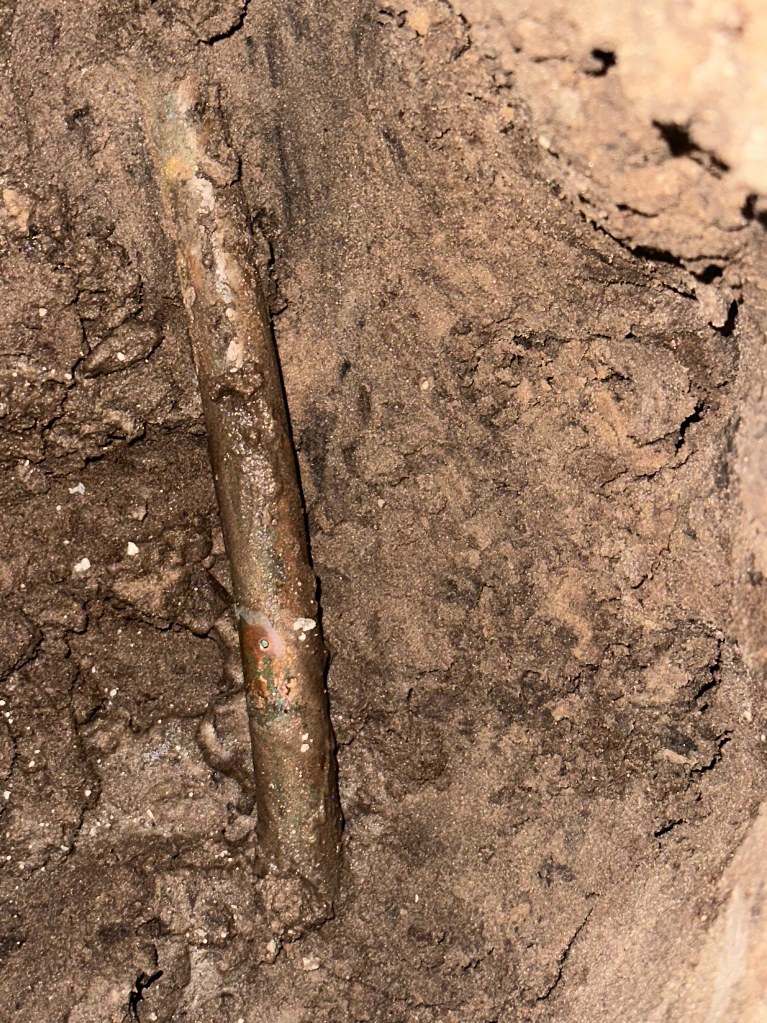 Close-up of copper pipe pinhole leak beneath slab causing high water bill in Clearwater home