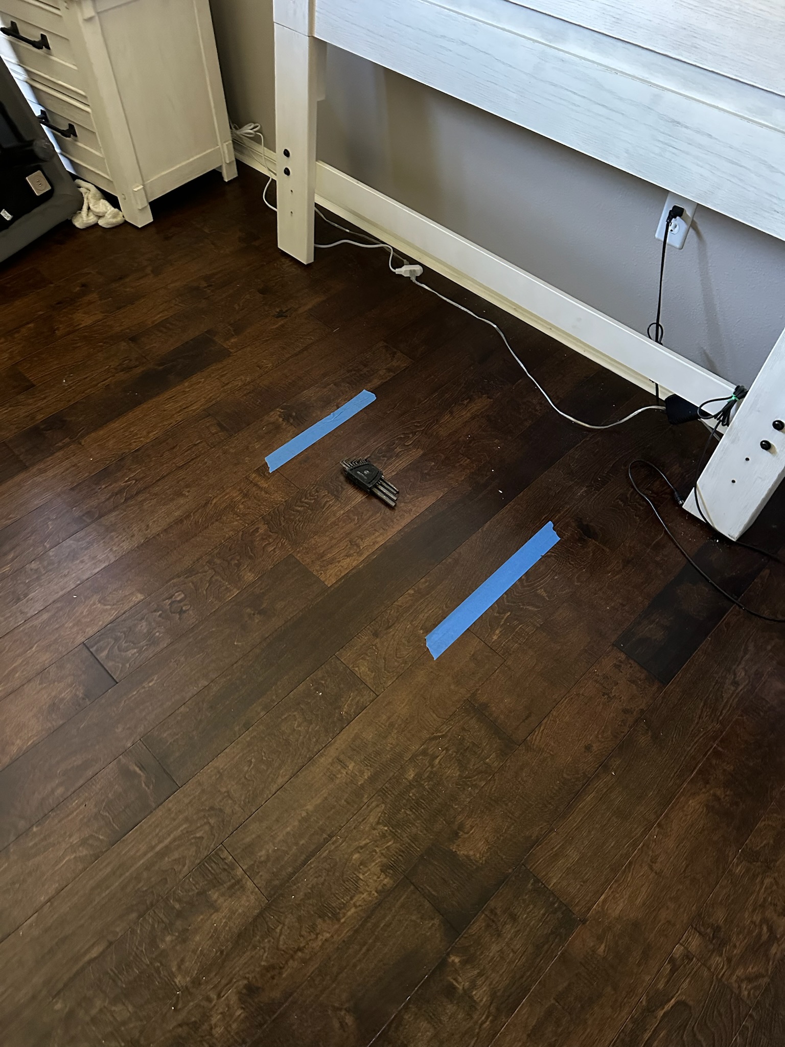 Oldsmar Water Leak Detection - Bedroom Wood Floor Marked Location Blue tape marking a suspected leak location on a glue-down wood bedroom floor during an Oldsmar water leak detection inspection.