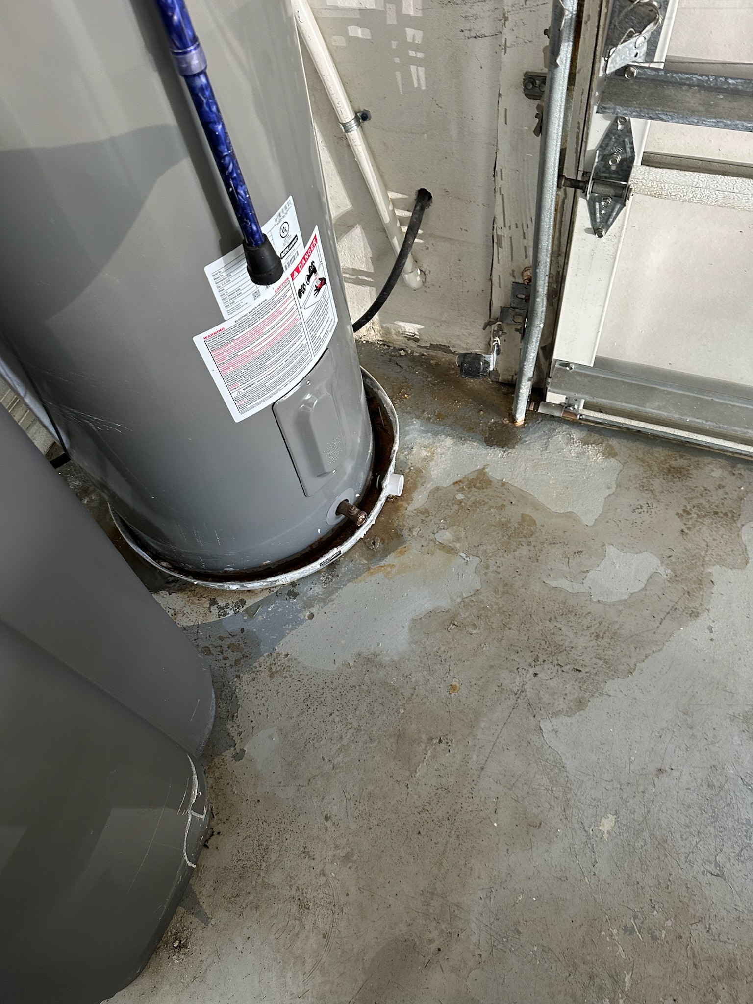 Oldsmar Water Leak Detection - Garage Water Near Water Heater Water running across an Oldsmar garage floor near a water heater and out under the garage door before leak detection inspection.