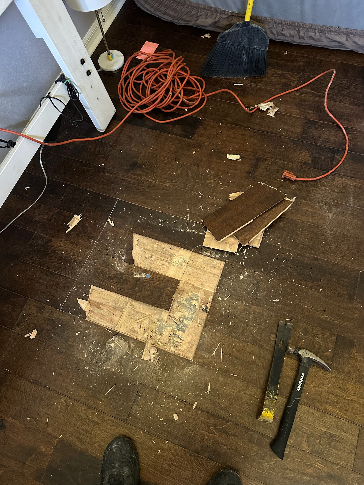 Oldsmar Water Leak Detection - Wood Floor Removal at Verified Location Hammer and chisel used to remove glue-down wood flooring at a verified bedroom leak location during an Oldsmar leak detection inspection.