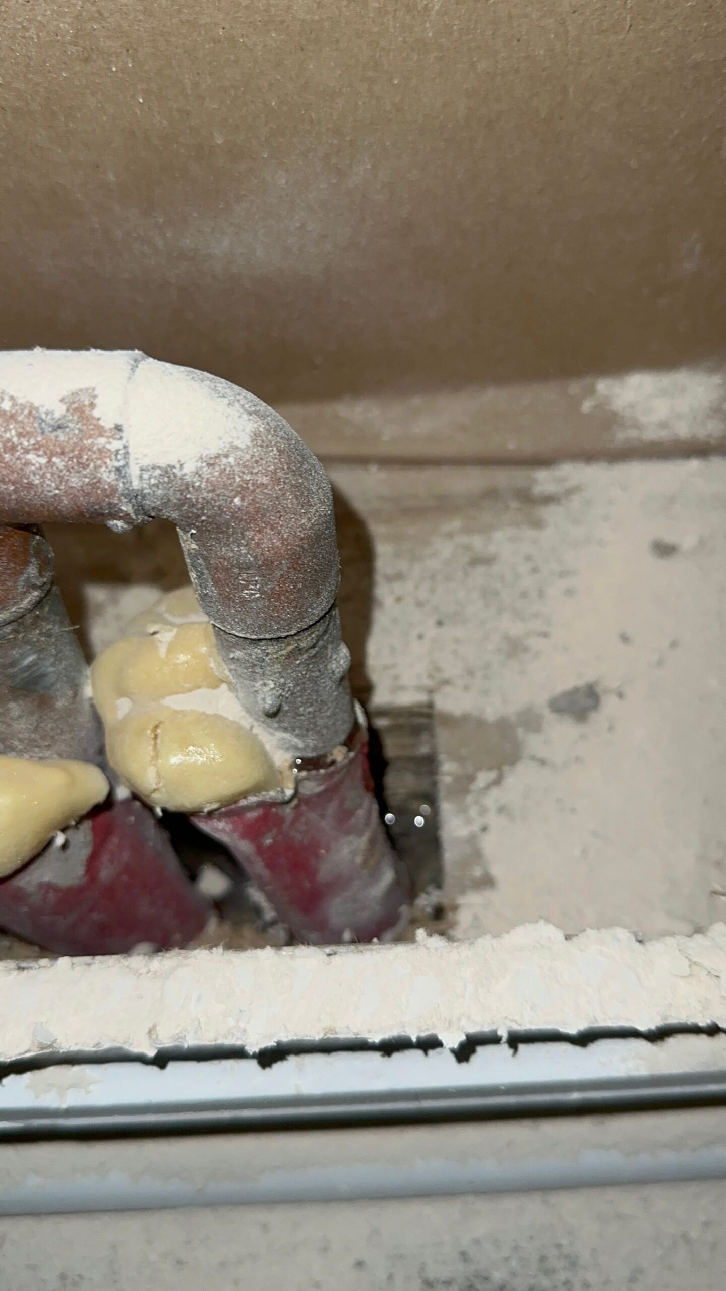 Close-up of leaking copper pipe and red protective sleeve causing wet carpet in St. Petersburg home