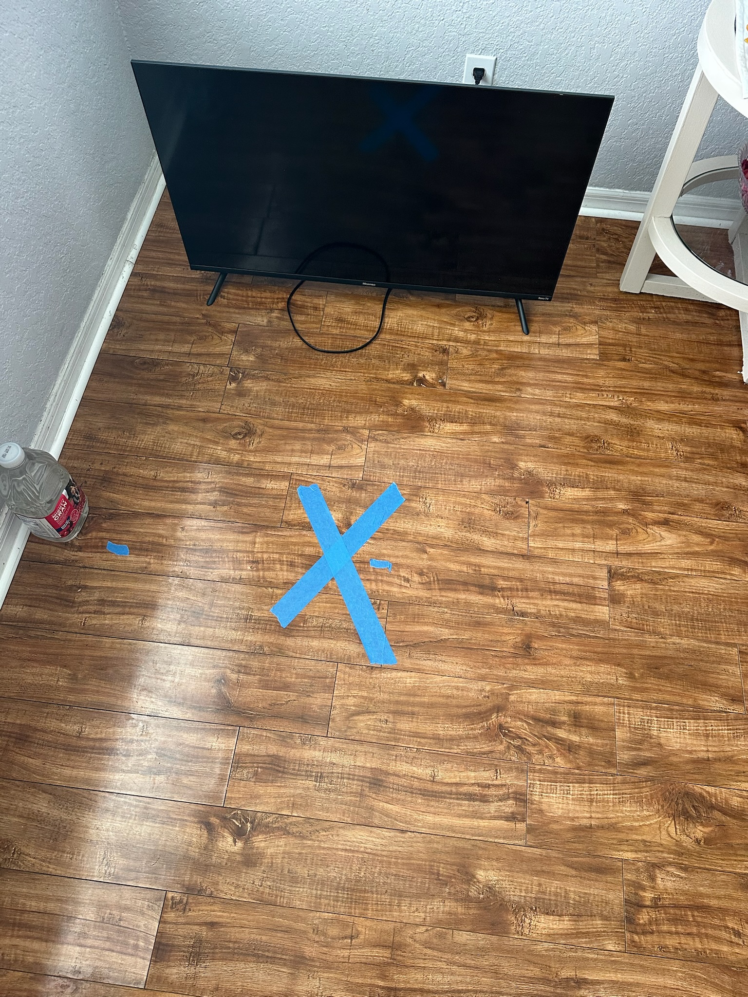 Pinellas County slab leak blue X marked on finished wood floor Blue X marks suspected slab leak location on finished wood floor during Pinellas County high water bill investigation