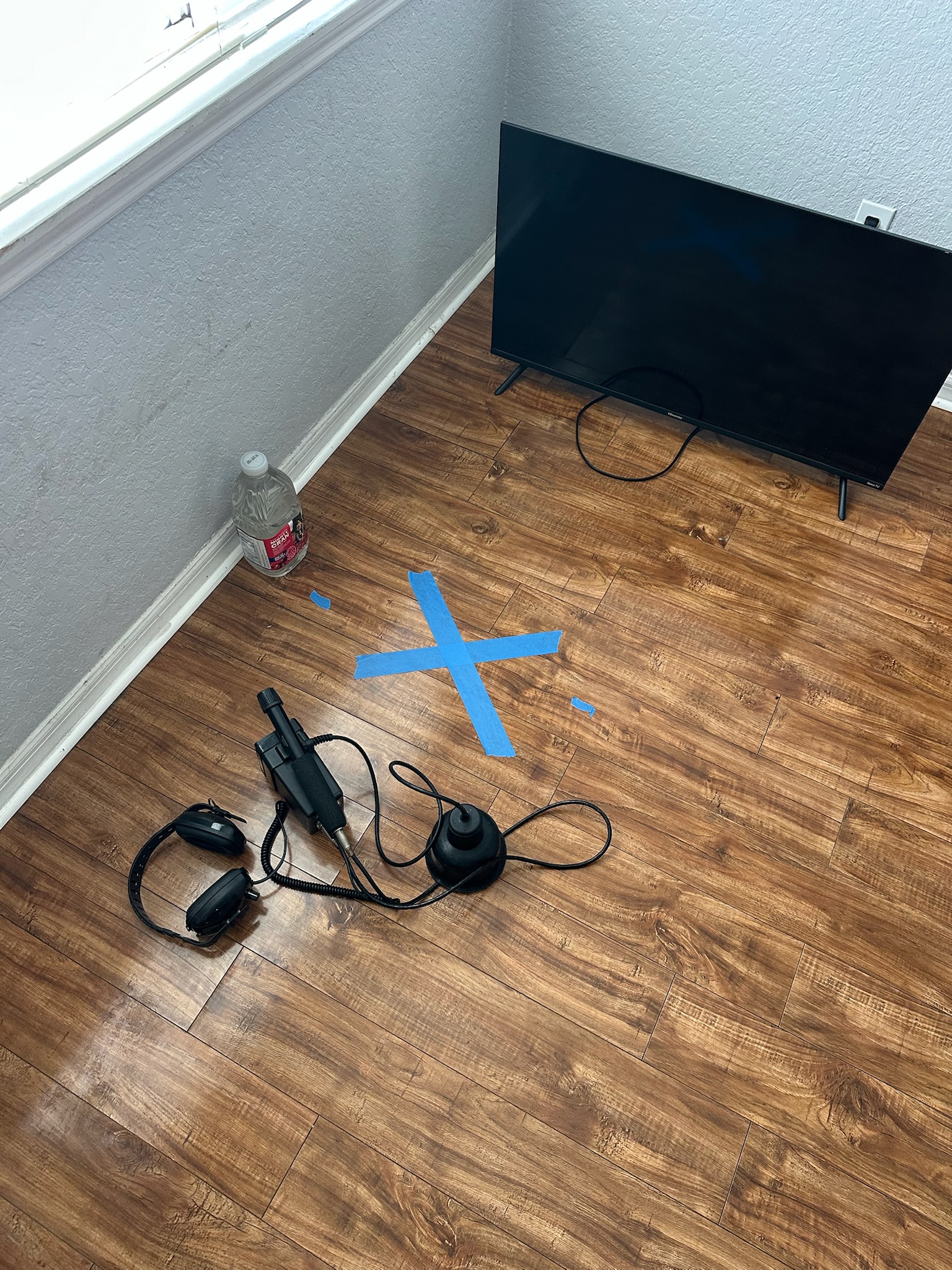 Pinellas County high water bill slab leak location marked with blue X Blue X marks suspected slab leak location on wood floor during Pinellas County high water bill investigation