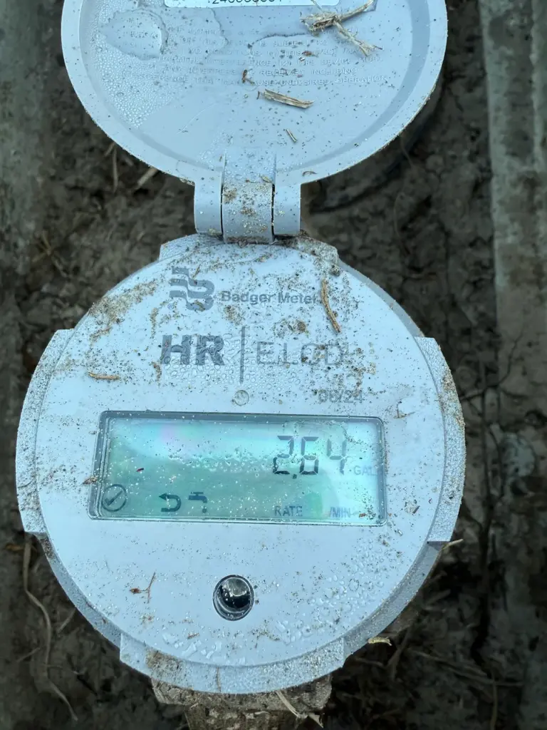 Digital water meter register with the lid flipped open, its display reading 2.64.