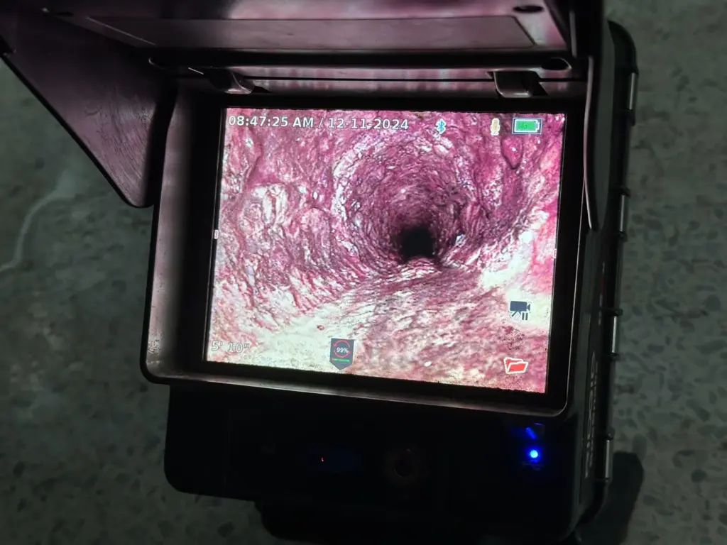Sewer camera monitor displaying a live view down the inside of a drain pipe.