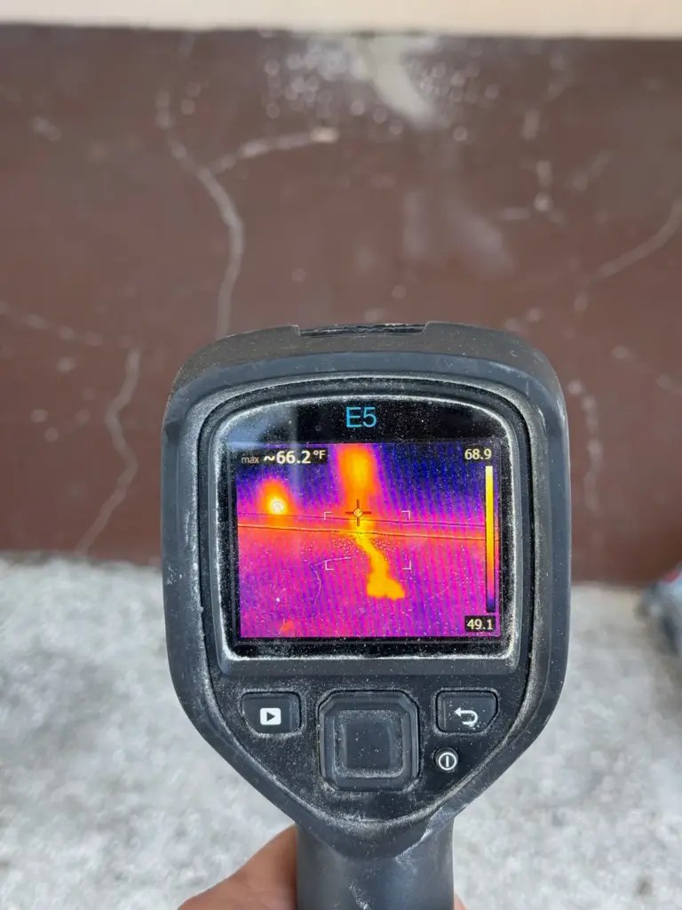 Thermal camera screen showing a bright warm trail running across a cooler purple floor.