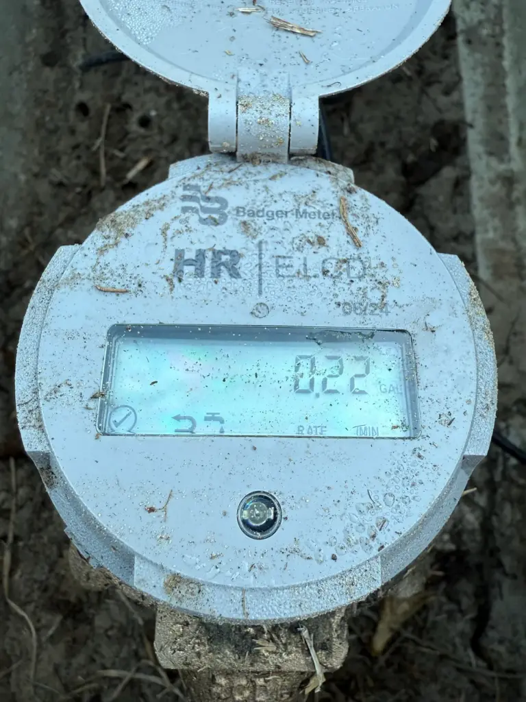 Digital water meter register in a meter box with the lid open, its display reading 0.22.