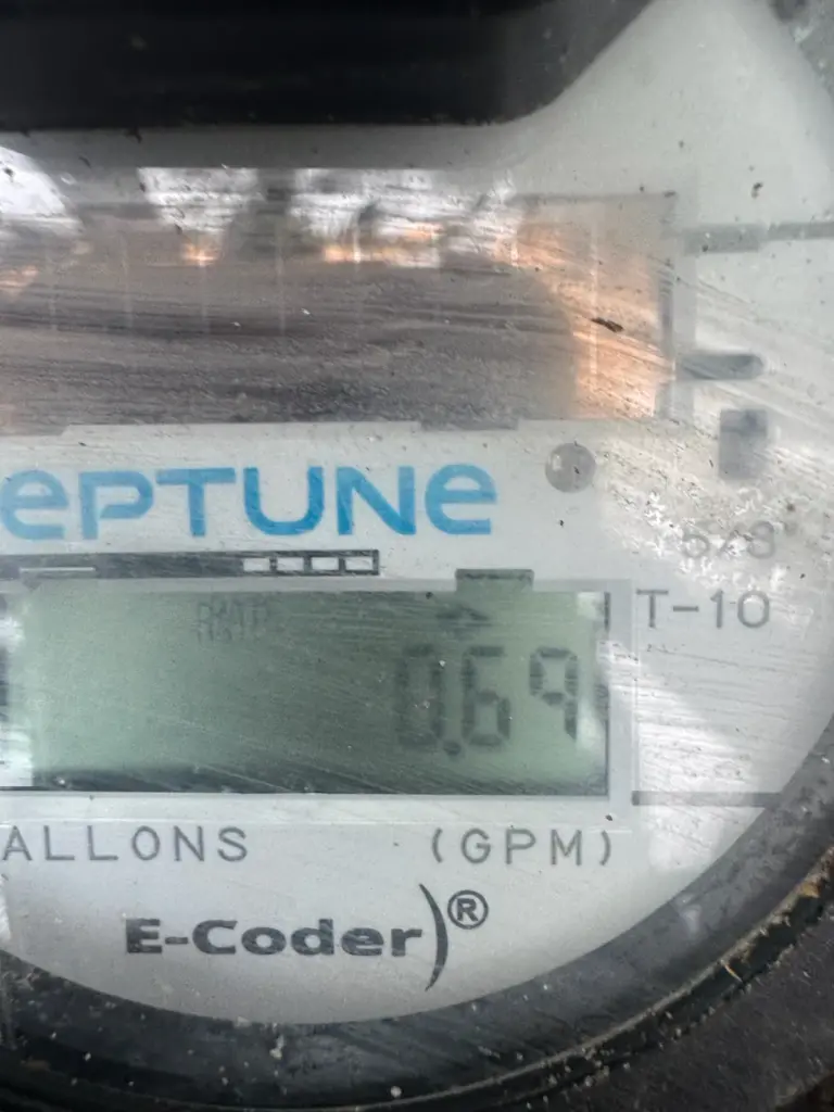Digital water meter display showing an active flow reading in gallons per minute.